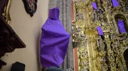 Patung perempuan ditutupi dengan kain ungu di Gereja De los Santos Cosme y Damian di Mexico City, pada Rabu (4/3/2020). Penutupan patung tersebut sebagai bentuk protes terhadap kekerasan gender. (Photo by Pedro PARDO / AFP)