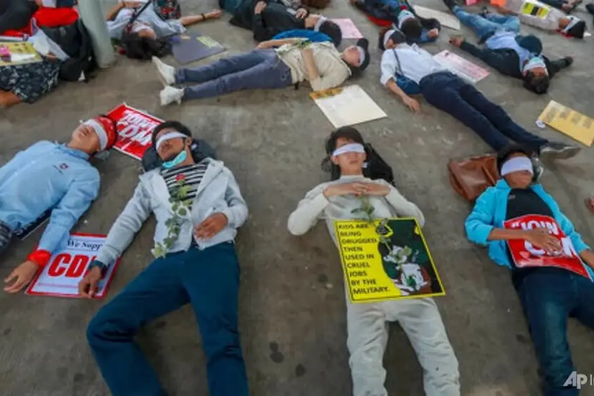 Demonstran, dengan mata tertutup, berbaring di jalan untuk memprotes kudeta militer di Yangon, Myanmar, pada 16 Februari 2021. (Foto: AP)