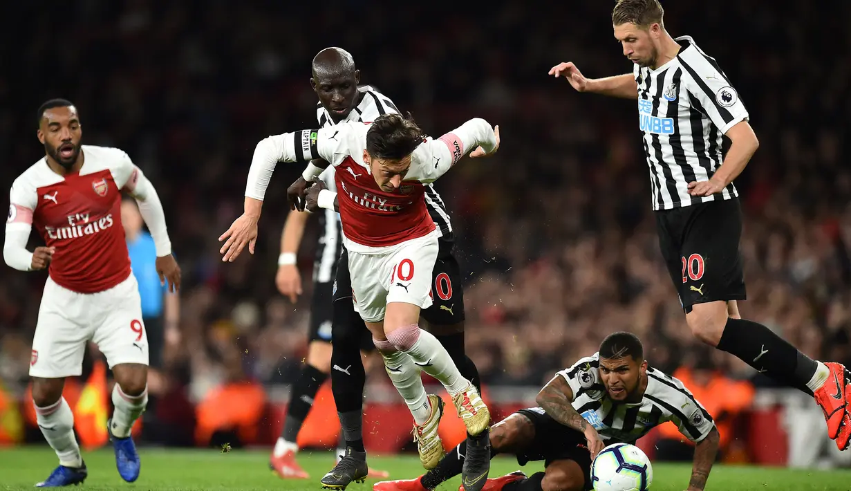 Gelandang Arsenal, Mesut Oezil (tengah) dikepung tiga pemain Newcastle United pada laga Liga Inggris 2018/2019 di Emirates Stadium, London (1/4/2019). Mesut Oezil tercatat membuat 4 gol dan 1 assist ke gawang Newcastle United saat berseragam Arsenal dari total 6 laga di Liga Inggris sejak musim 2013/2014 hingga 202/2021. (AFP/Glyn Kirk)