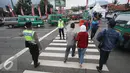 Petugas kepolisian membantu warga menyeberang jalan di Perempatan Cileunyi, Jawa Barat, Jumat (1/7). Mulai banyaknya kendaraan pemudik membuat petugas kepolisian membantu pejalan kaki yang ingin menyeberang. (Liputan6.com/Immanuel Antonius) 