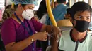 Seorang pekerja menerima suntikan vaksin Covid-19 Covishield di dalam bus penumpang yang diubah menjadi pusat vaksinasi keliling di Kolkata, Kamis (3/6/2021). India telah menderita pandemi yang menghancurkan sejak April, dan baru-baru ini mulai mereda. (Dibyangshu SARKAR/AFP)