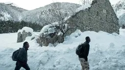 Imigran berjalan melintasi jalan yang dipenuhi salju untuk menuju perbatasan antara Italia dan Prancis di Pegunungan Alpen, Italia (13/1). Bahkan mereka melintasi salju pegunungan Alpen dengan pakain biasa bukan pakain untuk di Salju.(AFP/Piero Cruciatti)