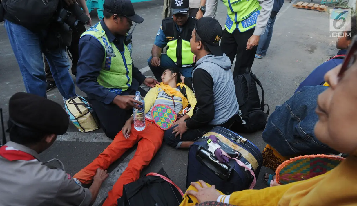 Petugas membantu pemudik yang pingsan setelah turun dari KM Labobar tiba di Pelabuhan Tanjung Perak, Surabaya, Jawa Timur, Jumat (31/5/2019). Pelindo III memprediksi puncak mudik angkutan laut Lebaran 2019 yang masuk ke Jawa Timur akan terjadi pada H-3 atau Minggu, 2 Juni. (merdeka.com/Dwi Narwoko)