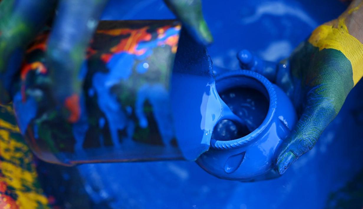 Seorang pembuat tembikar mewarnai lampu tanah jelang Festival Diwali di sepanjang pinggir jalan di New Delhi, India, 18 Oktober 2022. Festival Diwali atau dalam agama Hindu berarti Festival Cahaya melambangkan kemenangan baik atas keburukan, dan lampu atau pelita dinyalakan sebagai tanda perayaan serta harapan umat manusia. (Sajjad HUSSAIN/AFP)