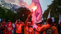 Seorang pengunjuk rasa menyalakan suar dalam aksi unjuk rasa peringatan Hari Buruh Internasional (May Day) di Surabaya, Jawa Timur, pada Kamis 1 Mei 2025. (Juni KRISWANTO/AFP)