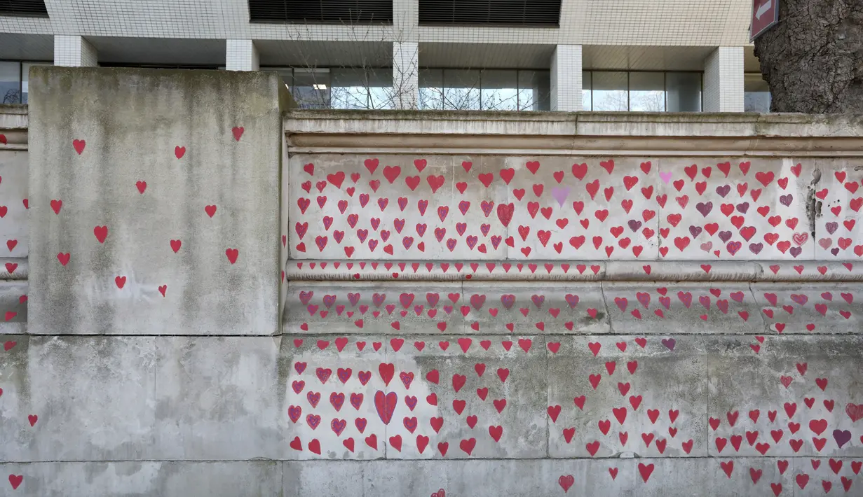 Gambar hati dilukis oleh seorang anggota keluarga yang berduka di Tembok Peringatan COVID-19, di seberang Gedung Parlemen, di London, Senin (29/3/2021). Mural hampir 150.000 lukisan hati itu untuk mengenang ribuan orang yang meninggal akibat virus corona di Inggris. (Lucianna Guerra/PA melalui AP)