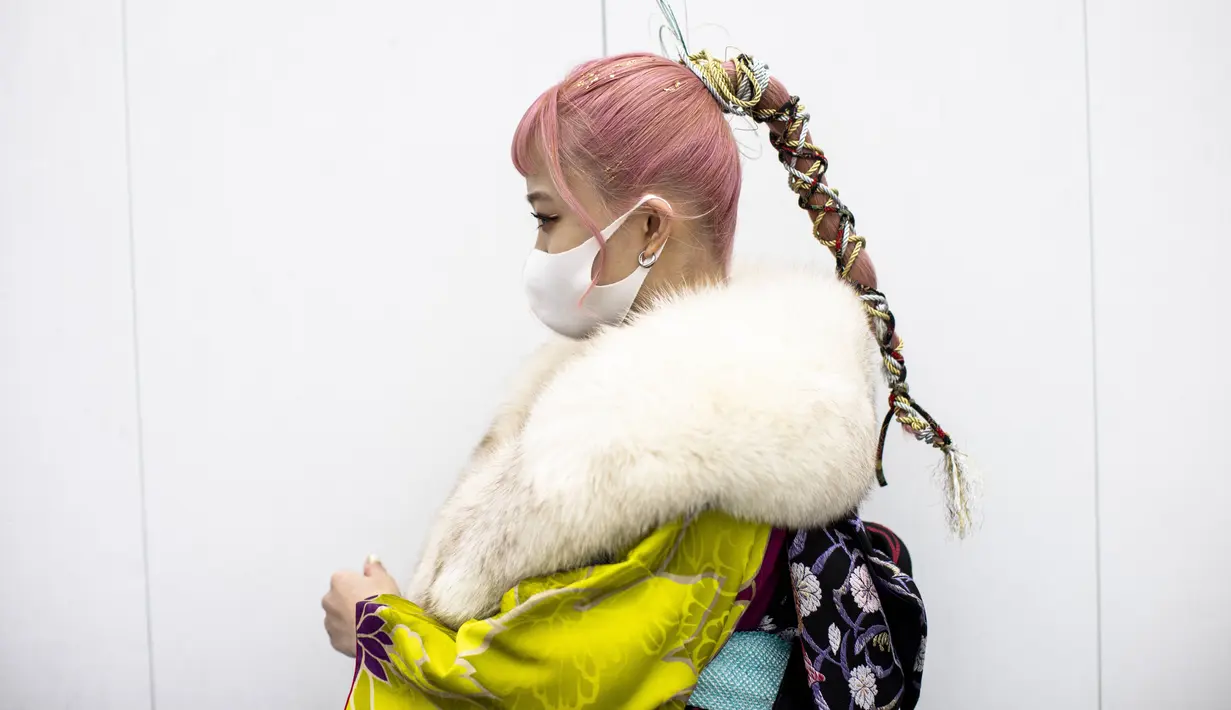 Miu Sakunaga Jepang berusia 20 tahun mengenakan kimono dengan rambut dikuncir berpose di luar Todoroki Arena selama upacara perayaan "Coming-of-Age Day" di Kawasaki, prefektur Kanagawa (11/1/2021). (AFP/Behrouz Mehri)