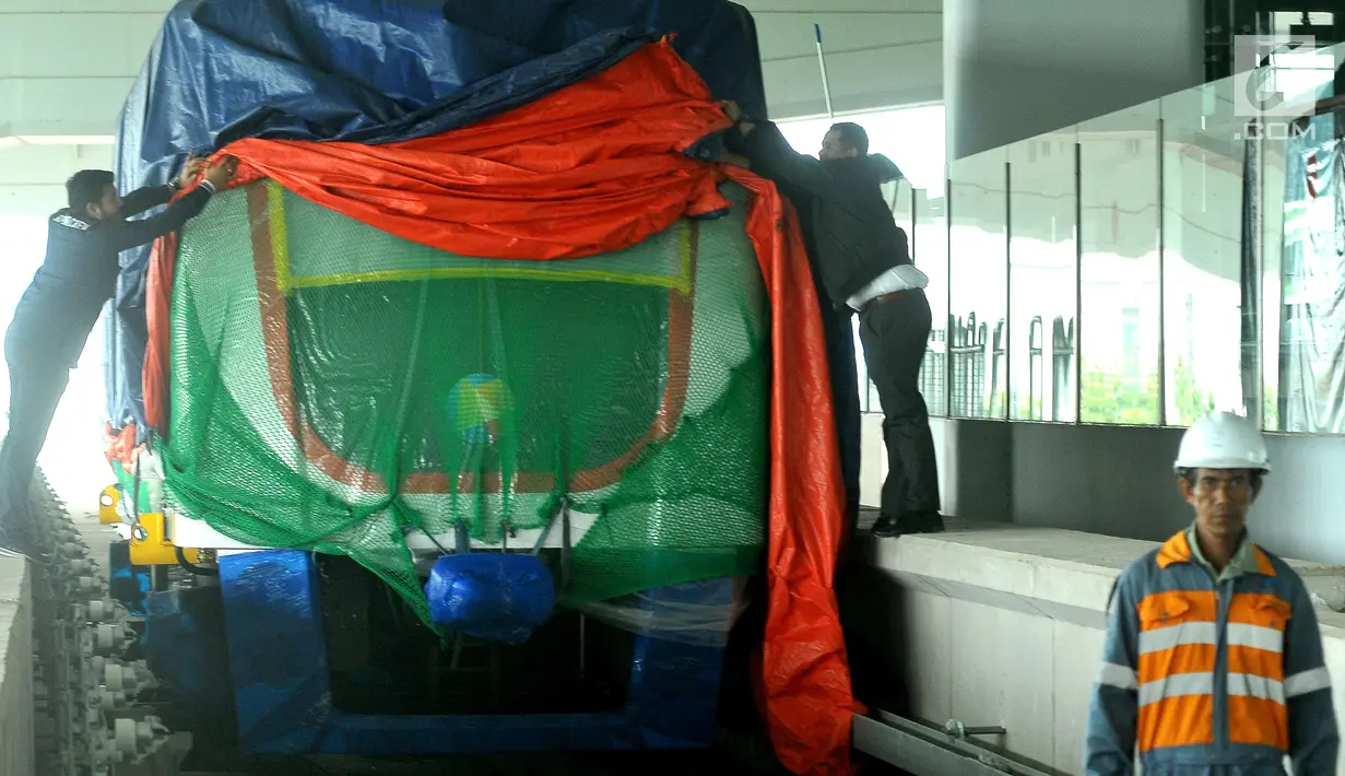 Pekerja membuka selubung skytrain atau automated people mover system (APMS) yang baru dipasang di Terminal 3 Bandara Soekarno Hatta, Tangerang, Selasa (30/5). Rencananya Kereta tanpa awak ini akan di uji pertengahan Juni . (Liputan6.com/Helmi Afandi)