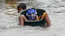 Seorang bocah mendorong rekannya yang menaiki ember menyebrangi jalan yang terendam banjir di Kota Longos, Malabon City, Manila Utara, Senin (6/7/2015). Akibat badai aktivitas penerbangan, pelabuhan dan sekolah-sekolah ditutup. (REUTERS/Romeo Ranoco)