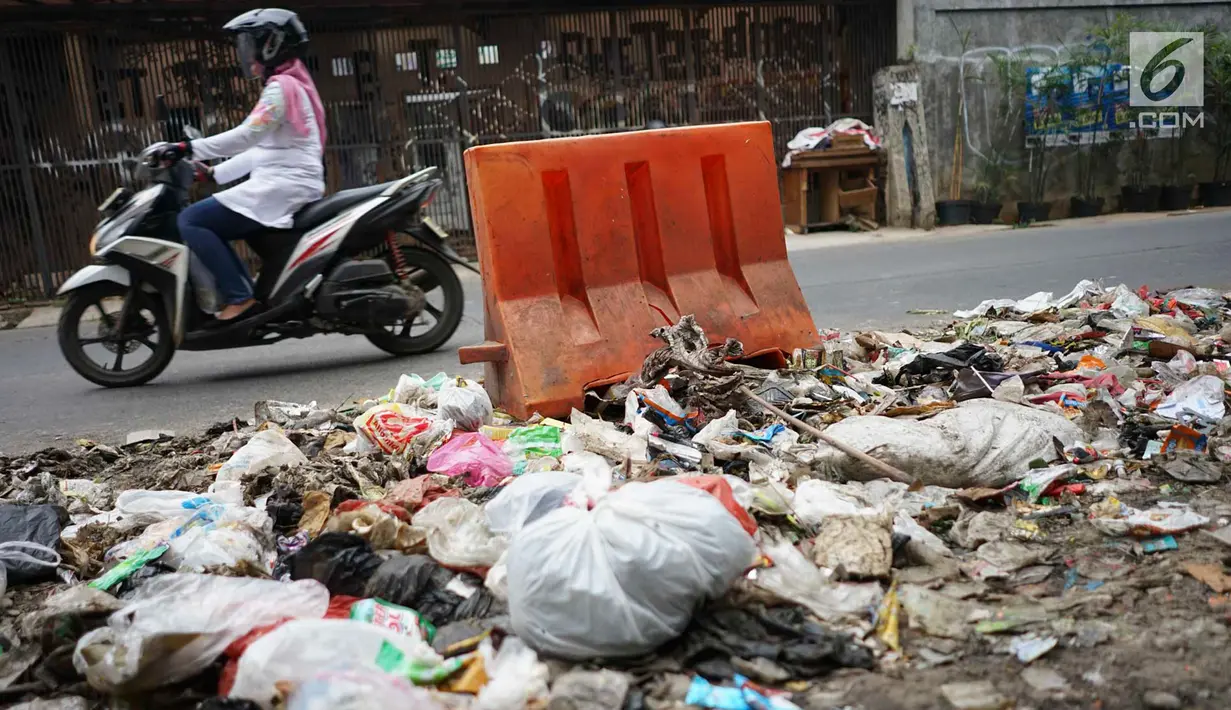 Pengendara melintasi tumpukan sampah rumah tangga di Jalan Raya Tanah Baru kawasan Depok, Jawa Barat, Rabu (15/5/2019). Kurangnya tempat penampungan membuat warga terpaksa membuang sampah di lokasi tersebut, meskipun menimbulkan bau tidak sedap serta mengotori jalan. (Liputan6.com/Immanuel Antonius)