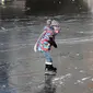 Seorang anak asyik berseluncur melintasi permukaan kanal Prinsengracht yang membeku di Amsterdam, Belanda, Jumat (2/3). Mereka sekarang bisa bermain ice skating di kanal-kanal yang melewati kota. (AP/Mike Corder)