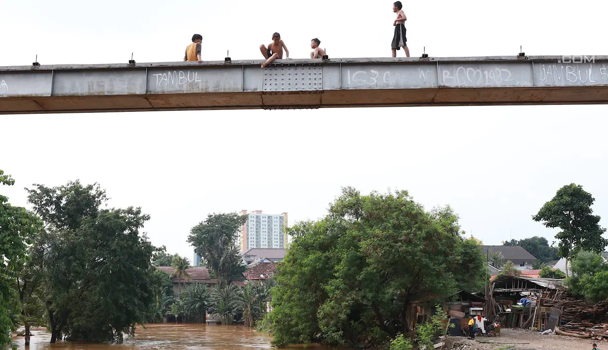 Anak-anak bersiap melompat ke Sungai Ciliwung yang meluap di kawasan Rawajati, Jakarta, Jumat (26/4). Tingginya volume debit air yang berasal dari Bogor tidak menyurutkan niat anak-anak itu untuk tetap berenang, meskipun berbahaya bagi keselamatan. (Liputan6.com/Immanuel Antonius)