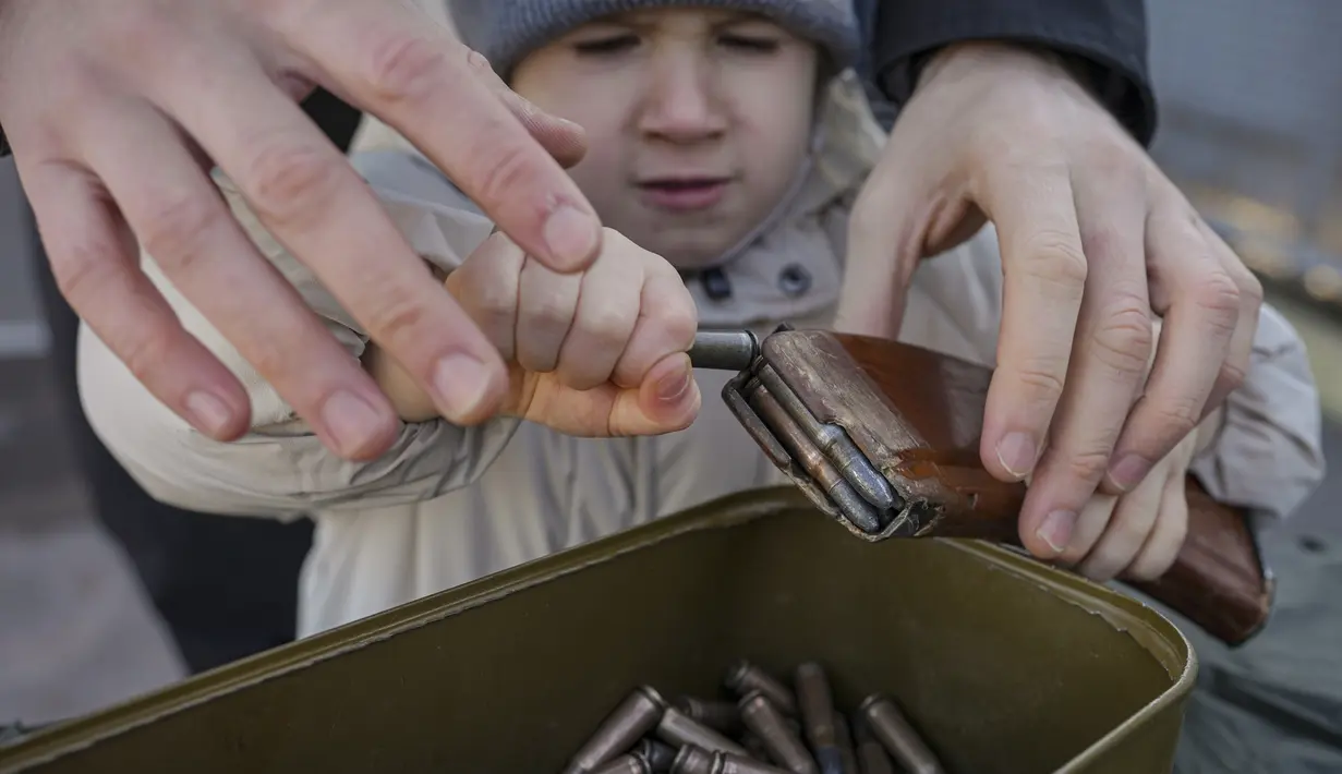 Seorang anak kecil mengeluarkan amunisi selama pelatihan perang dasar untuk warga sipil, oleh Unit Pasukan Khusus Azov, dari Garda Nasional Ukraina, di Mariupol, wilayah Donetsk, Minggu (13/2/2022). Mereka disiapkan untuk bisa bertahan di tengah kekhawatiran akan invasi Rusia (AP Photo/Vadim Ghirda)