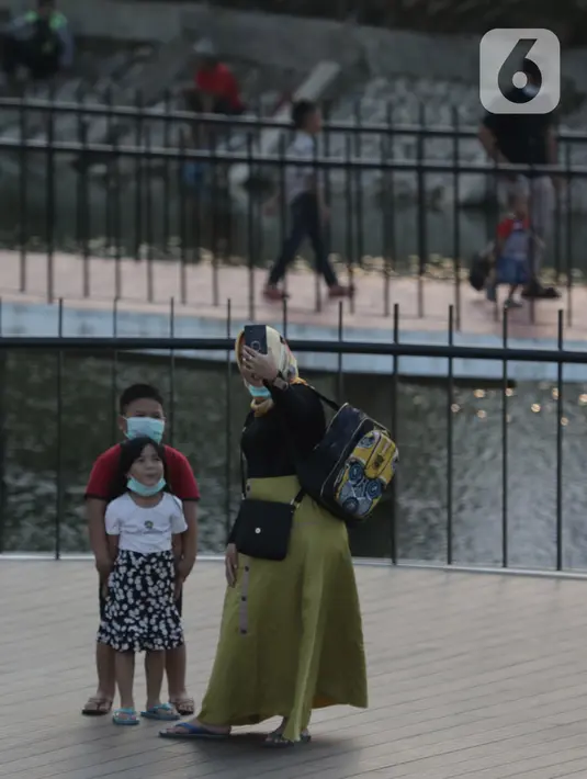 Keluarga foto bersama saat menunggu berbuka puasa di Waduk Mookervart di Kalideres, Jakarta Barat, Minggu (9/5/2021). Waduk Mookervart tersebut dimanfaatkan oleh warga sekitar untuk ngabuburit atau menunggu waktu berbuka puasa tiba. (Liputan6.com/Angga Yuniar)
