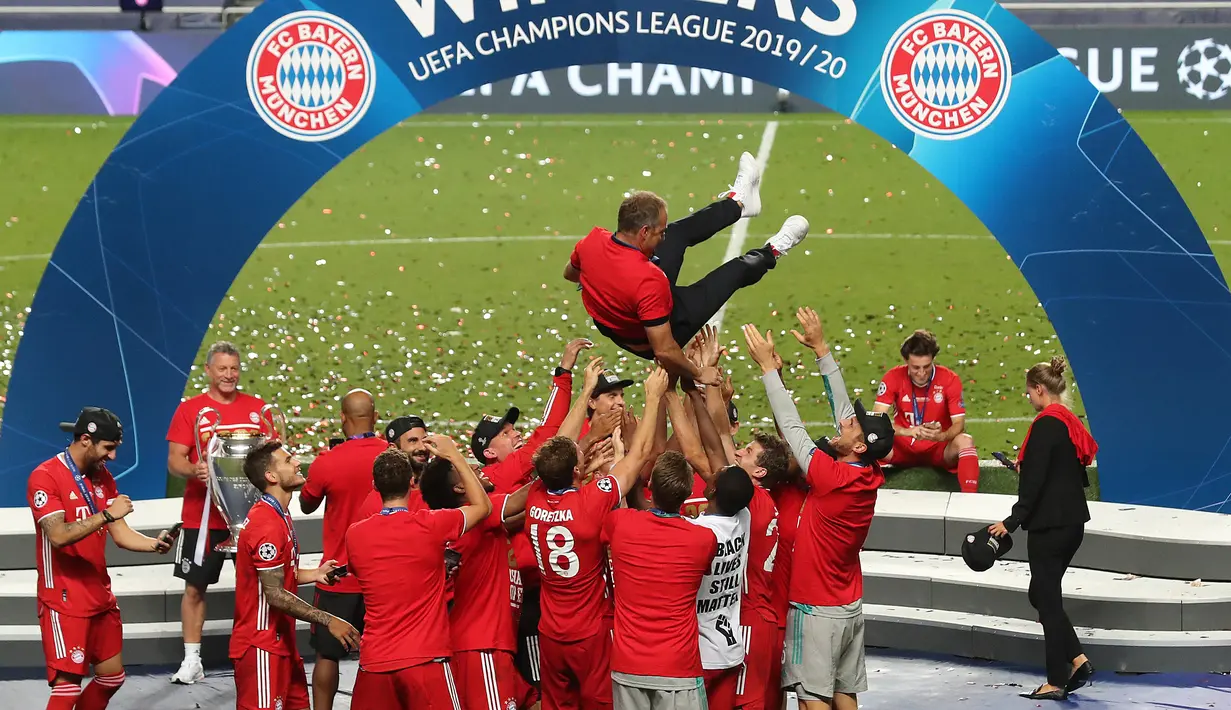Pelatih Bayern Munchen, Hans-Dieter Flick dilempar oleh para pemain saat merayakan kemenangan atas PSG pada pertandingan final Liga Champions di stadion Luz di Lisbon (23/8/2020). Munchen menang tipis atas PSG 1-0. (AFP/Pool/Miguel A.Lopes)