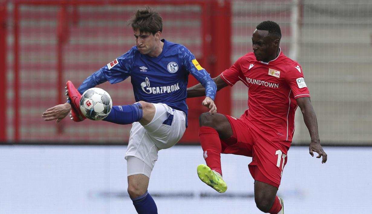 Pemain Union Berlin, Anthony Ujah, berebut bola dengan pemain Schalke, Juan Miranda, pada laga Bundesliga di Weserstadion Minggu (7/6/2020). Kedua tim bermain imbang 1-1. (AP/Michael Sohn)