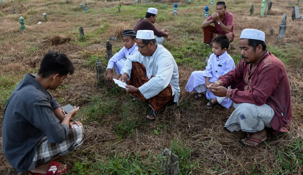 Muslim Thailand berdoa saat menziarahi kuburan kerabat mereka pada perayaan Idul Adha di provinsi Narathiwat, Minggu (11/8/2019). Pada setiap Idul Adha atau menyambut hari besar Islam sebagian warga banyak mendatangi kuburan untuk mendoakan keluarganya. (Madaree TOHLALA/AFP)