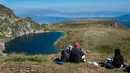 Sejumlah orang menyaksikan anggota gerakan keagamaan internasional White Brotherhood menari di puncak Gunung Rila, Bulgaria, Senin (19/8/2019). White Brotherhood didirikan oleh teolog Bulgaria Peter Deunov pada tahun 1897. (NIKOLAY DOYCHINOV/AFP)