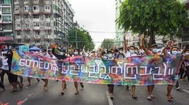 Pengunjuk rasa memberi hormat tiga jari sambil memegang spanduk bertuliskan, "Bukit dan Wilayah Tengah bersatu" di Yangon (3/6/2021). Demonstran pro-demokrasi turun ke jalan di kota-kota di Myanmar untuk mengecam militer, menandai empat bulan sejak menggulingkan pemerintah terpilih. (AFP/STR)