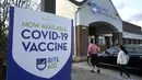 Orang-orang berjalan melewati tanda vaksin COVID-19 ketika mereka memasuki apotek Rite Aid di Nashua, New Hampshire, 7 Desember 2021. Ketika AS mencapai tonggak sejarah dengan sekitar 200 juta orang telah divaksinasi penuh, infeksi dan rawat inap justru mengalami lonjakan. (AP Photo/Steven Senne)