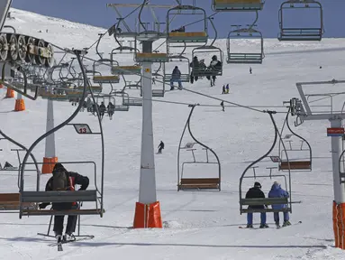Pemain ski menggunakan kursi gantung di resor ski Tochal di luar ibu kota Teheran, Iran (1/1/2022). Di tengah polusi udara dan kesengsaraan ekonomi, penduduk Teheran menemukan kenyamanan di resor ski di utara Teheran di pegunungan Alborz. (AP Photo/Vahid Salemi)