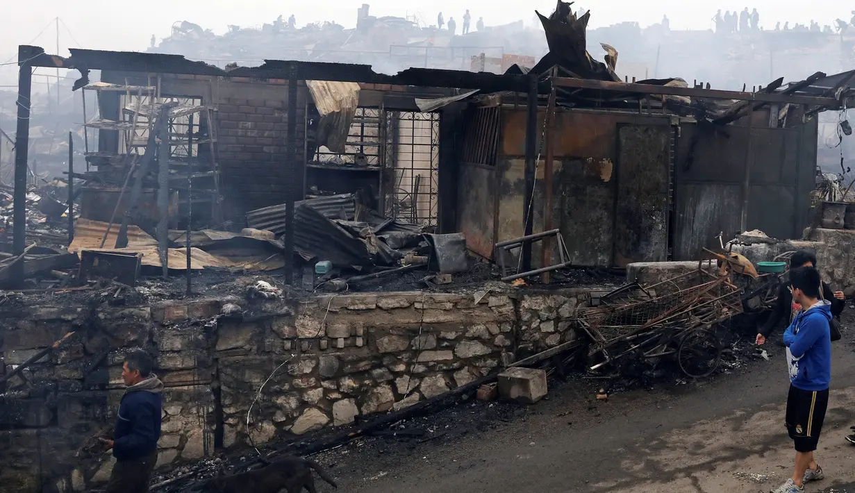 Warga berdiri di luar lokasi kebakaran besar yang melanda permukiman Cantagallo di Lima, Peru, Jumat (4/11). Pejabat setempat mengatakan, ada 46 orang yang sempat dirawat akibat terlalu banyak menghirup asap. (REUTERS/Guadalupe Pardo)