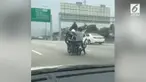 Seorang pengendara motor nekat membonceng seorang penumpang dan juga sebuah motor di jalanan ramai.