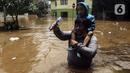 Warga menggendong seorang anak saat berjalan menyusuri banjir di kawasan Kemang, Jakarta, Sabtu (20/2/2021). Curah hujan yang tinggi menyebabkan kawasan tersebut terendam banjir setinggi orang dewasa. (Liputan6.com/Johan Tallo)