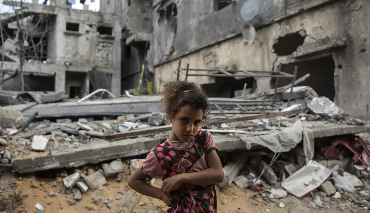 Warga Palestina Rahaf Nuseir (10) melihat saat berdiri di depan rumah keluarganya yang hancur di kota Beit Hanoun, Jalur Gaza, Jumat (21/5/2021). Israel dan Hamas telah sepakat untuk gencatan senjata setelah 11 hari pertempuran. (AP Photo/ Khalil Hamra)