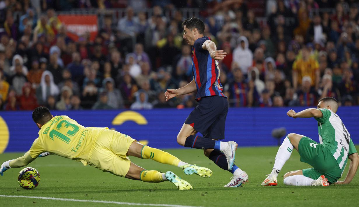 Pemain Barcelona, Robert Lewandowski, berusaha mencetak gol ke gawang Real Betis pada laga Liga Spanyol di Stadion Camp Nou, Minggu (30/4/2023). Empat gol Barcelona dicetak Andreas Christensen, Robert Lewandowski, Raphinha dan gol bunuh diri Guido Rodriguez. (AP Photo/Joan Monfort)