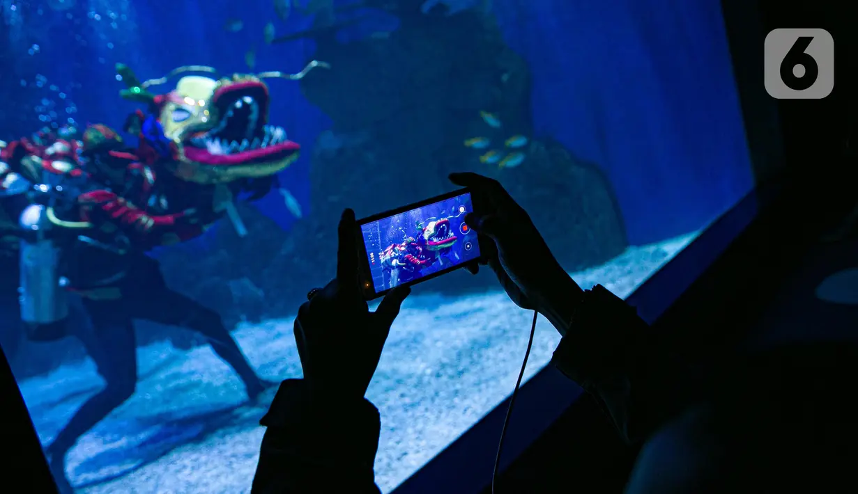 Pengunjung mengambil gambar atraksi Liong di Jakarta Aquarium & Safari (JAQS), Jakarta Barat, Jumat (12/2/2021). Pertunjukan Liong Show bawah air yang diikuti oleh para putri duyung tersebut untuk memeriahkan Hari Raya Imlek 2572 atau Tahun Baru China. (Liputan6.com/Faizal Fanani)