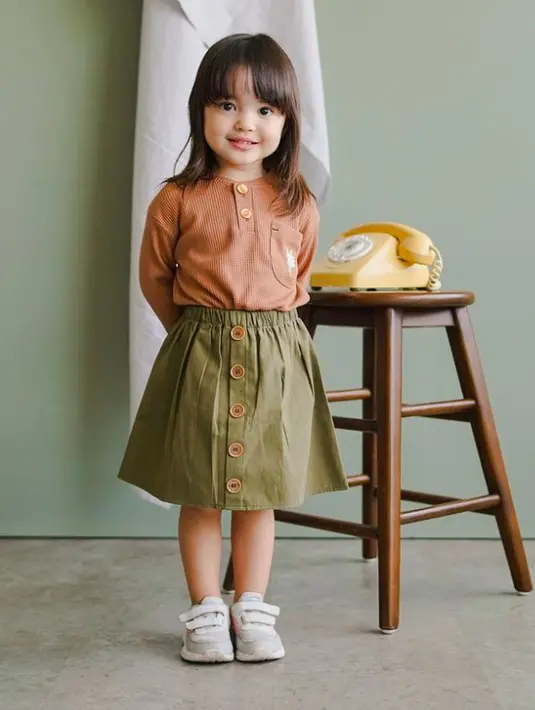 Perpaduan longsleeve top dan buttoned skirt dari Mooi nampak harmonis! Warna earth tone seperti hijau army dan oranye ternyata semakin membuat penampilan anak menjadi manis. (instagram.com/mooiofficial)