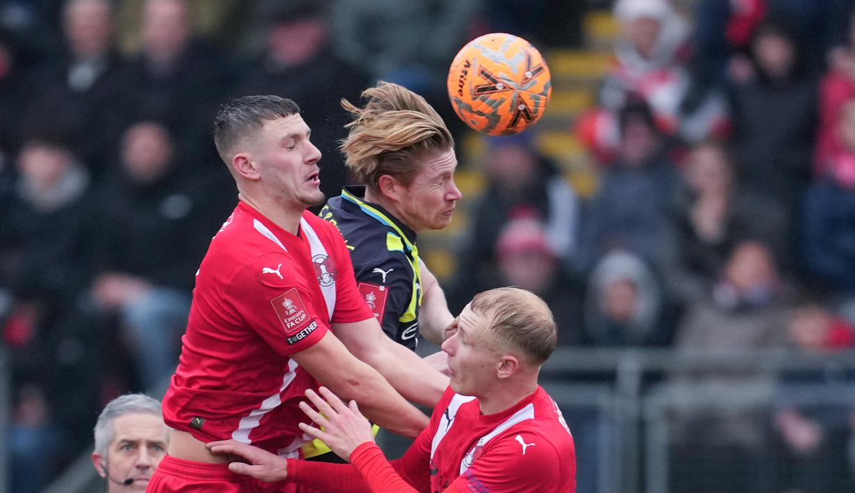 Pemain Manchester City, Kevin De Bruyne duel udara dengan pemain Leyton Orient dalam laga putaran keempat FA Cup 2024/2025 yang dihelat di Brisbane Road, London, Sabtu (8/2/2025) malam WIB. (AP Photo/Kin Cheung)