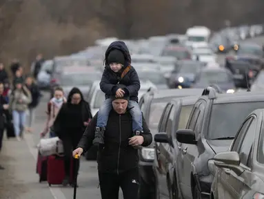 Pengungsi Ukraina berjalan di sepanjang kendaraan yang berbaris untuk menyeberangi perbatasan dari Ukraina ke Moldova, di titik perbatasan persimpangan Mayaky-Udobne, Ukraina, 26 Februari 2022. Lebih dari sekitar 500.000 orang terpaksa meninggalkan Ukraina selama invasi Rusia (AP Photo/Sergei Grits)