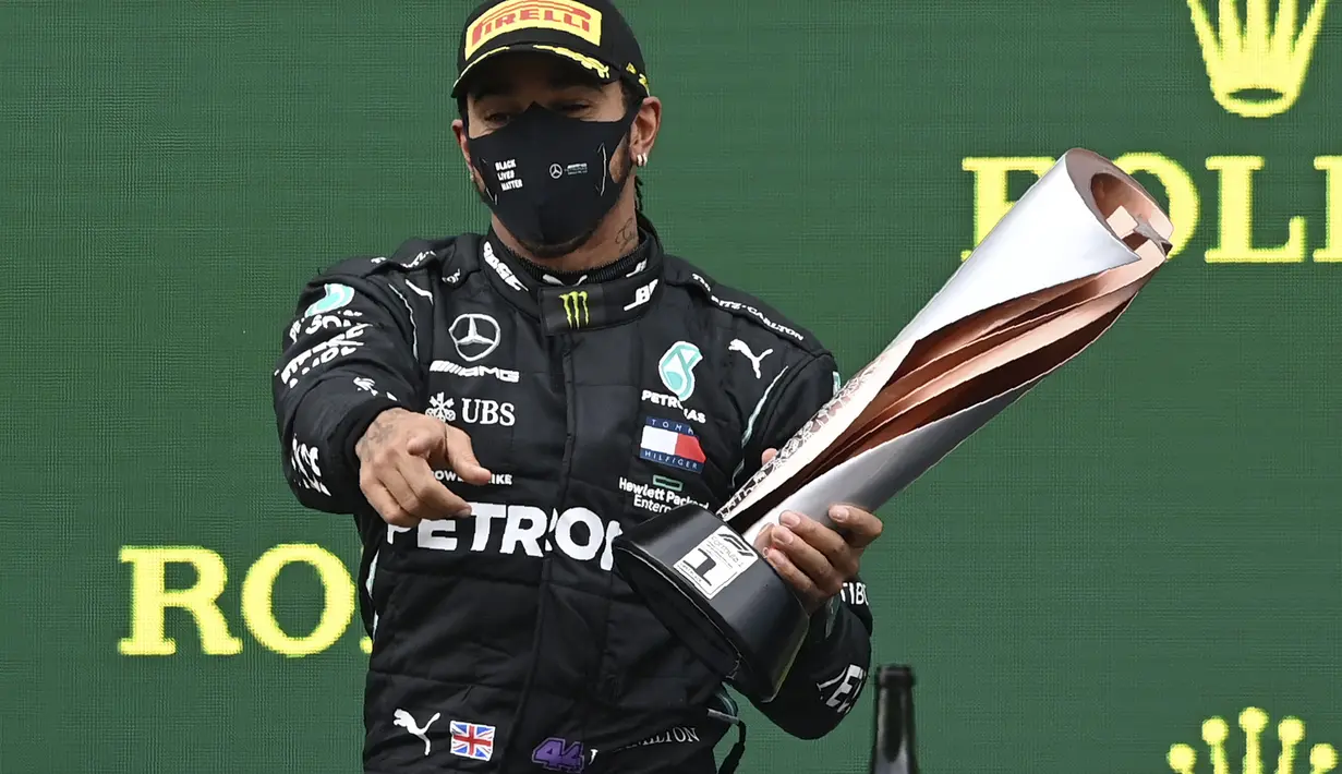 Pembalap Mercedes Lewis Hamilton berpose dengan piala saat merayakan kemenangan Grand Prix Formula Satu Turki di arena pacuan kuda Istanbul Park di Istanbul, Minggu (15/11/2020). (Ozan Kose/Pool via AP)