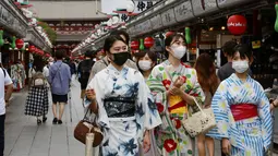 Wanita mengenakan yukata dan masker untuk melindungi diri dari penyebaran virus corona berjalan di jalan perbelanjaan Asakusa Nakamise di Tokyo, Jumat (13/8/2021). Yukata dipakai agar badan menjadi sejuk di sore hari atau sesudah mandi malam berendam dengan air panas. (AP Photo/Koji Sasahara)