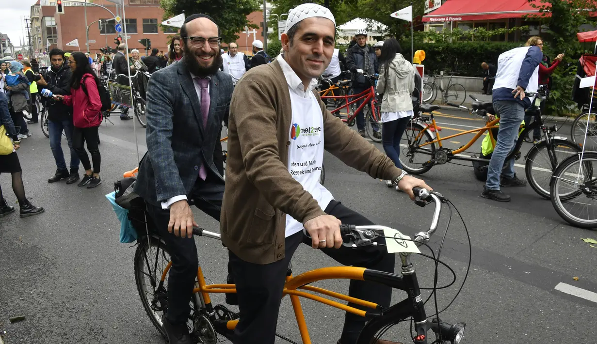 Imam Osman Oers (depan) dan Rabbi Akiva Weingarten mengayuh sepeda tandem sebagai kampanye lintas agama melintasi Ibu Kota Jerman, Berlin, 24 Juni 2018. Kegiatan ini untuk menunjukkan bahwa Muslim dan Yahudi bisa hidup berdampingan. (AFP/John MACDOUGALL)