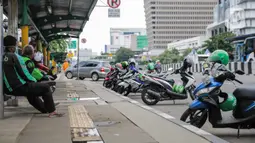 Sejumlah pengemudi ojek online beristirahat di sebuah halte di kawasan Harmoni, Jakarta, Selasa (7/4/2020). Selama pemberlakuan Pembatasan Sosial Berskala Besar (PSBB), layanan ojek online (ojol) akan dilarang mengangkut penumpang dan hanya dibolehkan untuk antar barang. (Liputan6.com/Faizal Fanani)