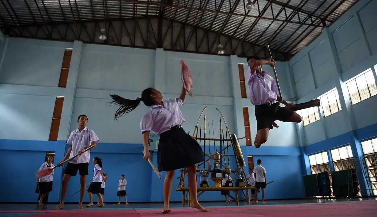 Seorang siswi menangkis serangan anak laki-laki yang menggunakan pedang selama berlatih Krabi Krabong di sekolah Thonburee Woratapeepalarak, Thonburi, Bangkok (8/7/2019). Krabi Krabong merupakan seni bela diri Thailand yang dipersenjatai pisau dan perisai kayu. (AFP Photo/Lillian Suwanrumpha)