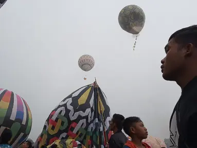 Seorang pria melihat balon udara dinaikan di Lapangan Pagerejo, Kertek, Kabupaten Wonosobo,  Sabtu (15/6/2019). Festival ini untuk memeriahkan syawalan dan wujud syukur warga yang hidup di lereng gunung sindoro dan sumbing. (Liputan6.com/Gholib)