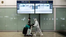 Penumpang mengenakan pakaian pelindung saat tiba di Bandara Internasional Hong Kong, Hong Kong (19/3/2020). Para penumpang di Bandara Hong Kong terpantau memakai perlindungan 'ekstra' lantaran takut tertular virus corona. (AFP/Anthony Wallace)