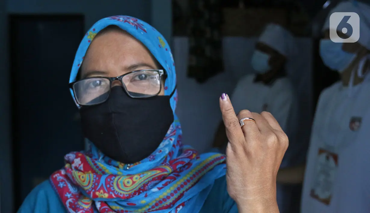 Warga menunjukkan jarinya yang telah ditandai tinta usai memberikan hak pilihnya dalam Pilkada Depok di TPS 56, Mekarjaya, Depok, Rabu (9/12/2020). TPS 56 menggunakan tema kesehatan untuk menarik warga menggunakan hak pilih dan mengingatkan protokol kesehatan COVID-19 (Liputan6.com/Herman Zakharia)