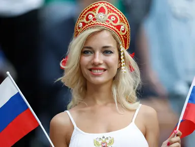 Suporter wanita tersenyum sambil memegang bendera Rusia sebelum pertandingan grup A Piala Dunia 2018 antara Rusia dan Arab Saudi di stadion Luzhniki di Moskow, (14/6). Dalam pertandingan ini, Rusia menang 5-0 atas Arab Saudi. (AP Photo/Antonio Calanni)