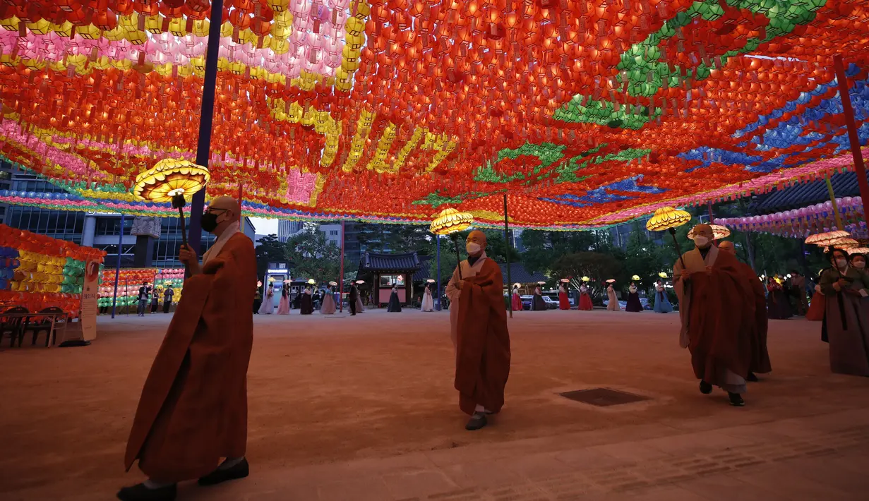Biksu dan pengikutnya mengenakan masker sambil menjaga jarak sosial sebagai pencegahan terhadap virus corona membawa lampion di kuil Jogye, Seoul, Korea Selatan (6/5/2021). Di negeri Ginseng ini, ulang tahun Buddha dirayakan dengan menggelar ‘Lotus Lantern Festival’. (AP Photo/Lee Jin-man)