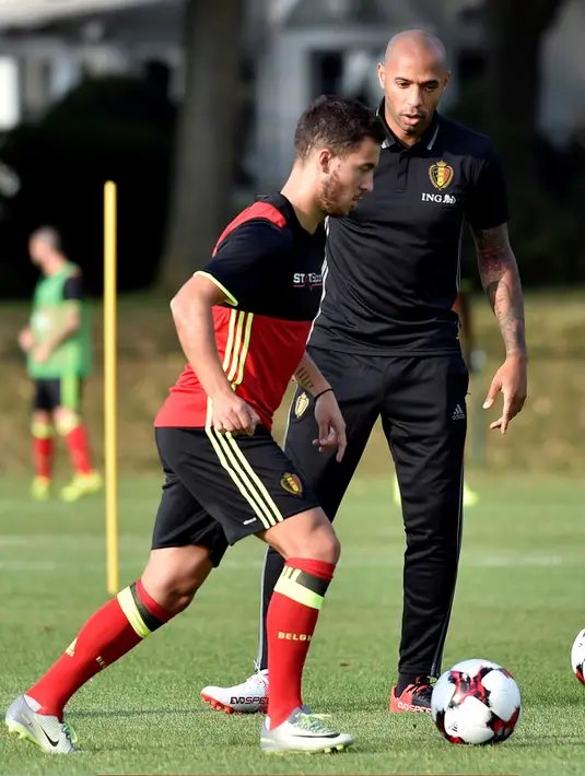 Mantan penyerang Timnas Prancis, Thierry Henry melihat gelandang Eden Hazard membawa bola saat sesi latihan di Neerpede, Belgia (29/8). Henry 39 tahun sebelumnya bekerja sebagai pelatih timi U-18 Arsenal. (REUTERS/Eric Vidal)