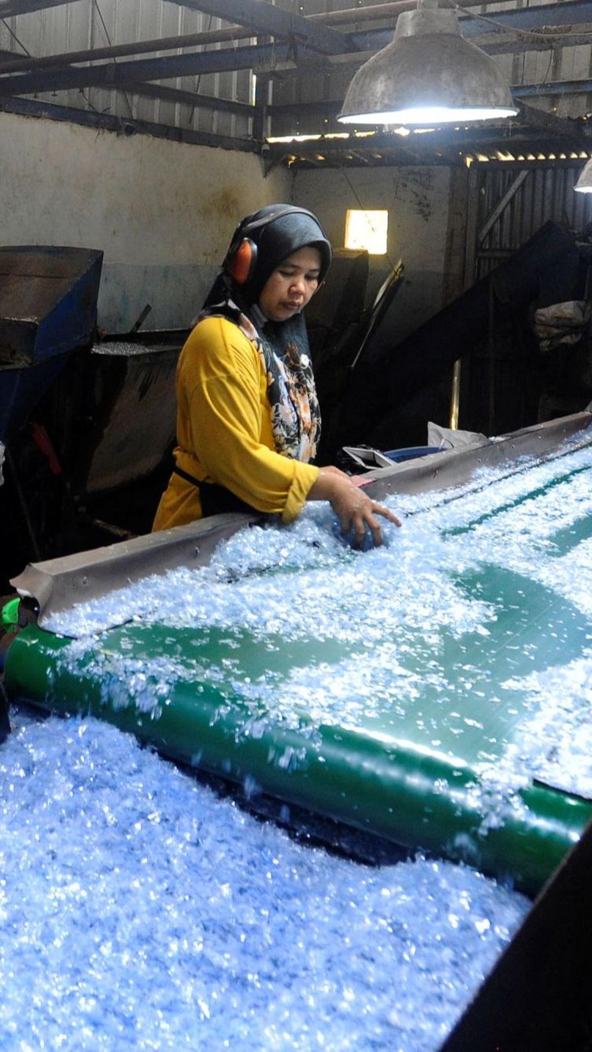 Seorang pekerja memilah plastik cacah di Koperasi Pemulung Berdaya. Hasil dari daur ulang plastik tersebut akan dipasarkan kepada perusahaan berbahan baku plastik.<br>