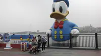 Wisatawan berswafoto di depan patung Donald Duck di taman hiburan Disneyland, Shanghai, China, Senin (11/5/2020). Saat ini Disneyland Shanghai hanya menerima pengunjung kurang dari 24 ribu orang, atau 30 persen dari kapasitas harian. (AP Photo/Chen Si)
