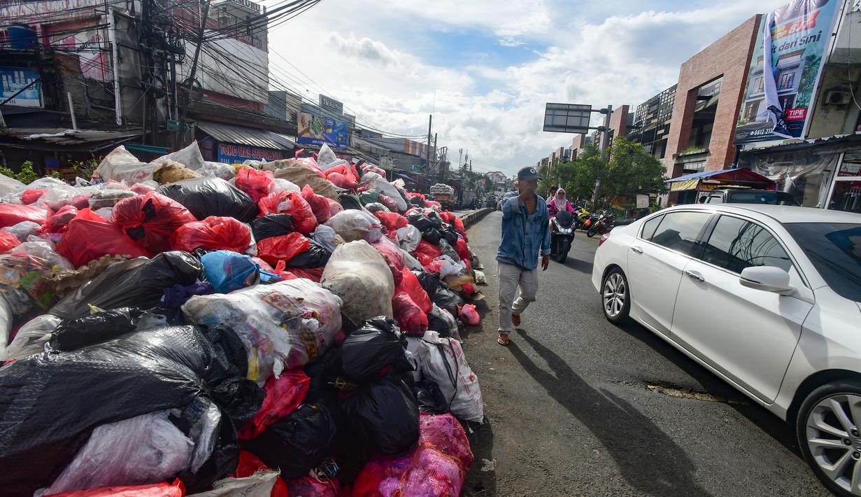 Aroma busuk pun merebak dan mengganggu kenyamanan warga maupun pengguna jalan. Tampak dalam foto, warga dan pengendara melintas di dekat tumpukan sampah diletakkan pada salah sisi satu ruas jalan di kawasan Pasar Manggis, Ciputat, Tangerang Selatan, Senin (15/12/2025). (merdeka.com/Arie Basuki)
