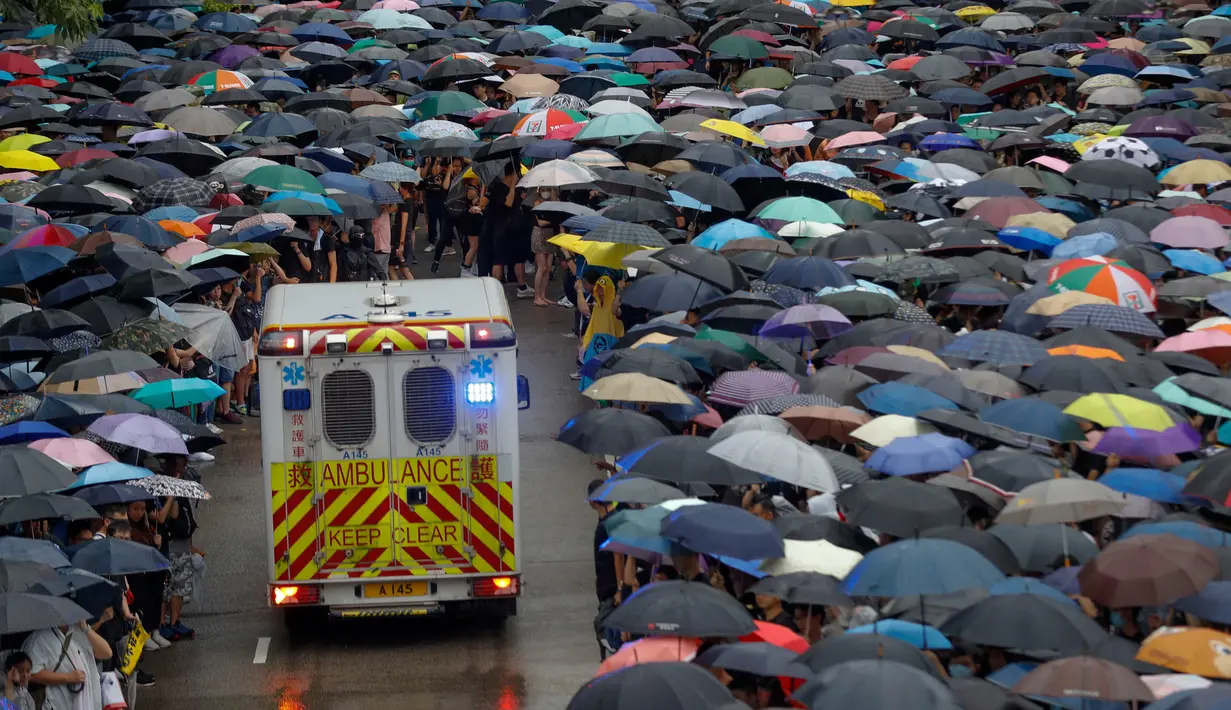 Pengunjuk rasa memberi ruang bagi ambulans yang melintas saat demonstrasi di Hong Kong, Minggu (18/8/2019). Puluhan ribu massa pro-demokrasi membawa payung saat hujan mengguyur Victoria Park dan sekitarnya. (AP Photo/Vincent Thian)