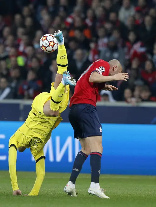 Bek Chelsea, Andreas Chistensen terjatuh saat berebut bola dengan penyerang Lille, Burak Yilmaz pada pertandingan leg kedua babak 16 besar Liga Champions di stadion Stade Pierre Mauroy, Prancis utara, Kamis (17/3/2022). Dengan hasil ini, Chelsea lolos ke babak perempat final. (AP Photo/Michel Spingl